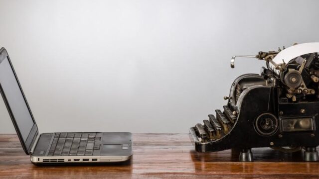 Vintage typewriter beside a modern laptop on a wooden desk, illustrating lessons from famous writers for content marketing