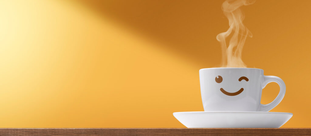 Smiling coffee cup with rising steam on a saucer against a warm orange background