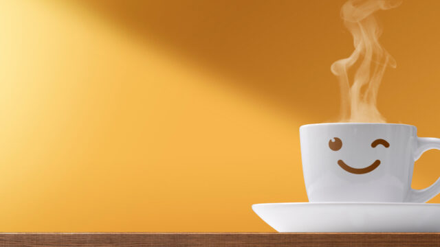 Smiling coffee cup with rising steam on a saucer against a warm orange background