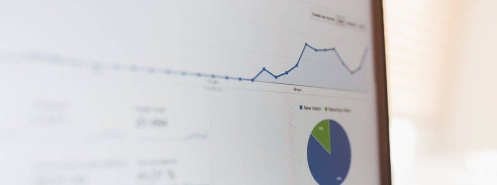 Analytics dashboard on a monitor showing a line chart with rising traffic and a pie chart of visitor segments