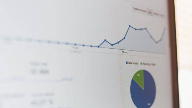 Analytics dashboard on a monitor showing a line chart with rising traffic and a pie chart of visitor segments