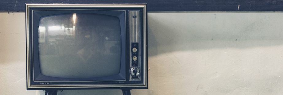 Vintage CRT television set against a plain wall, representing traditional advertising media
