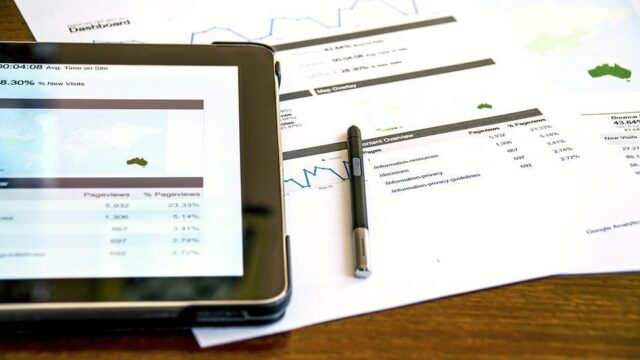Tablet and printed analytics reports on a desk showing Google Analytics dashboard data and statistics