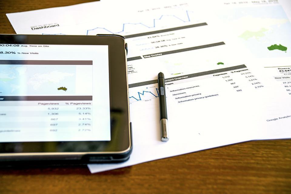 Tablet and printed analytics reports on a desk showing Google Analytics dashboard data and statistics