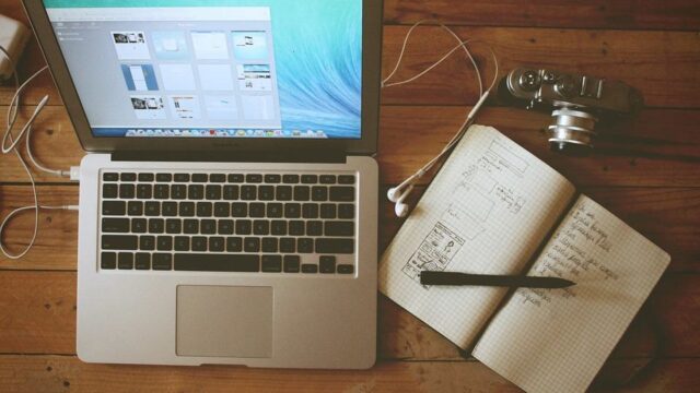 MacBook and open notebook with planning notes on a wooden desk, representing blogger outreach strategy