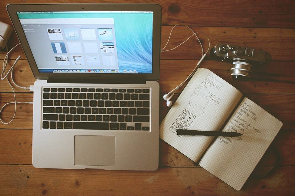 MacBook and open notebook with planning notes on a wooden desk, representing blogger outreach strategy