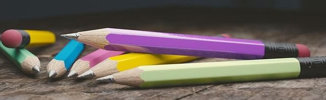 Colourful pencils scattered on a wooden surface, representing creative writing and copywriting