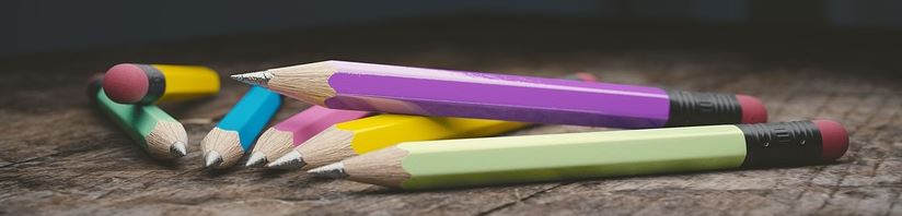 Colourful pencils scattered on a wooden surface, representing creative writing and copywriting