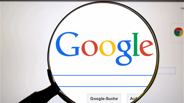 Magnifying glass over the Google homepage, illustrating scrutiny of Google's influence on elections and search