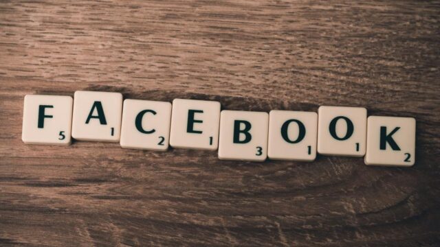 Scrabble tiles spelling FACEBOOK arranged on a wooden surface, representing Facebook advertising topics