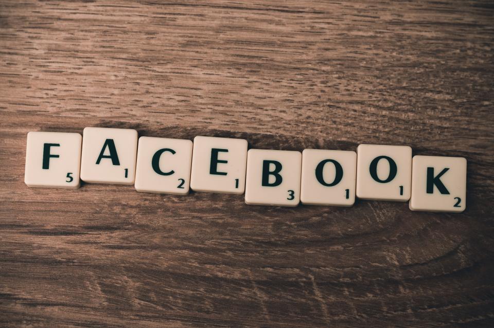 Scrabble tiles spelling FACEBOOK arranged on a wooden surface, representing Facebook advertising topics