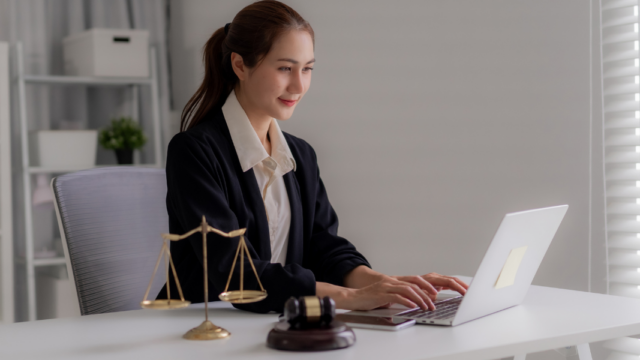 Female lawyer working on laptop at desk with scales of justice and gavel, representing digital marketing for family lawyers