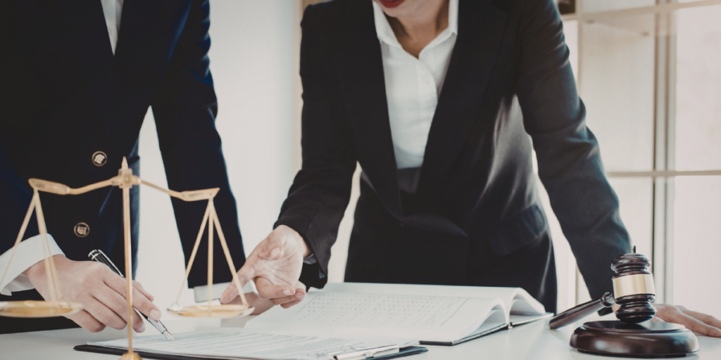 Two lawyers reviewing documents at a desk with scales of justice and gavel, representing legal digital marketing
