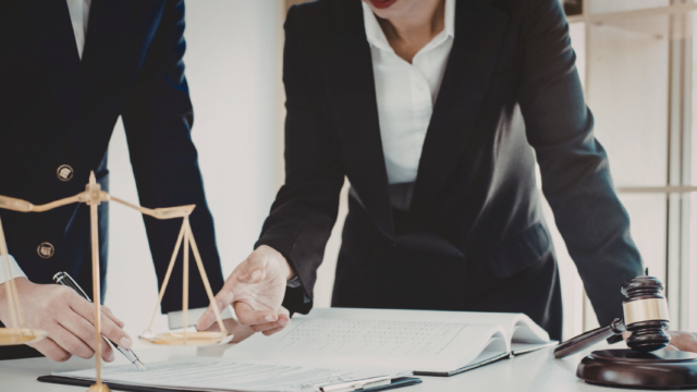 Two lawyers reviewing documents at a desk with scales of justice and gavel, representing legal digital marketing