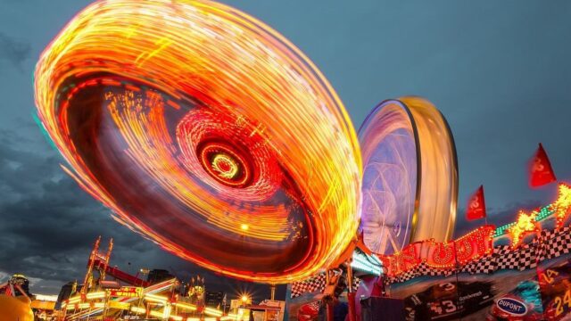 Spinning carnival ride with bright light trails at dusk, used as a fun and vibrant header for the fun stuff blog category
