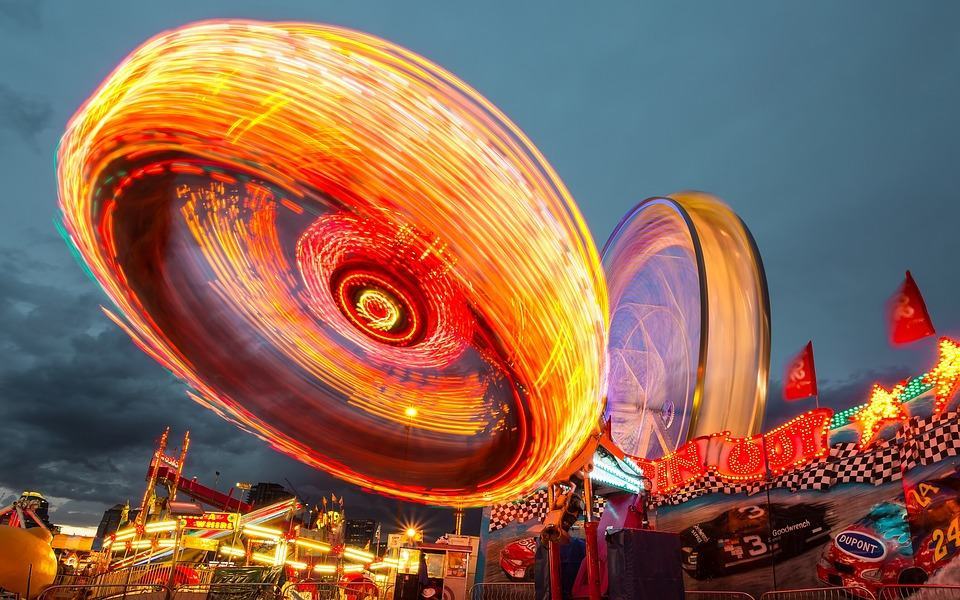 Spinning carnival ride with bright light trails at dusk, used as a fun and vibrant header for the fun stuff blog category