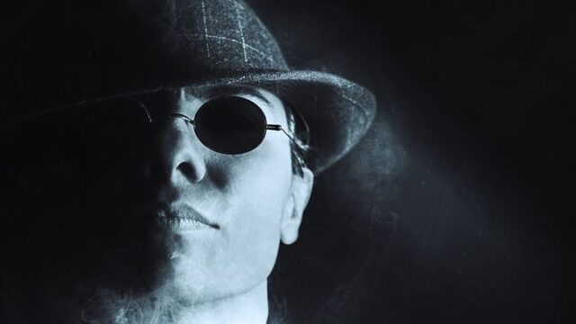 Moody black and white portrait of a man in a fedora and sunglasses, illustrating project management lessons from a gangster