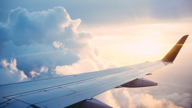 Airplane wing above clouds at golden hour, illustrating generating 50 blog ideas during a one-hour flight