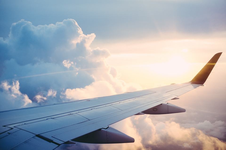 Airplane wing above clouds at golden hour, illustrating generating 50 blog ideas during a one-hour flight