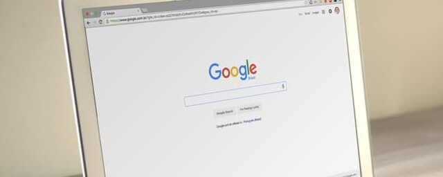 Laptop with Google homepage open on screen, angled side view on a light surface
