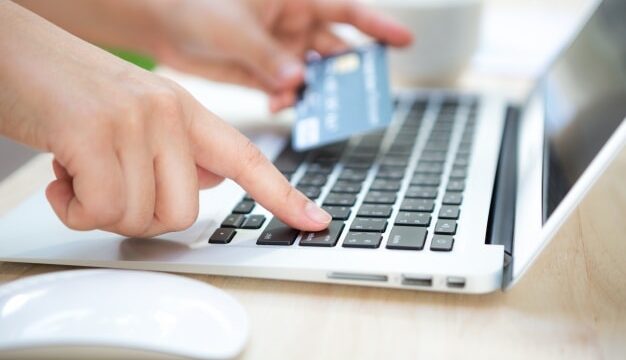 Hands typing on a laptop with a credit card in hand, illustrating online purchasing and conversion rate improvement