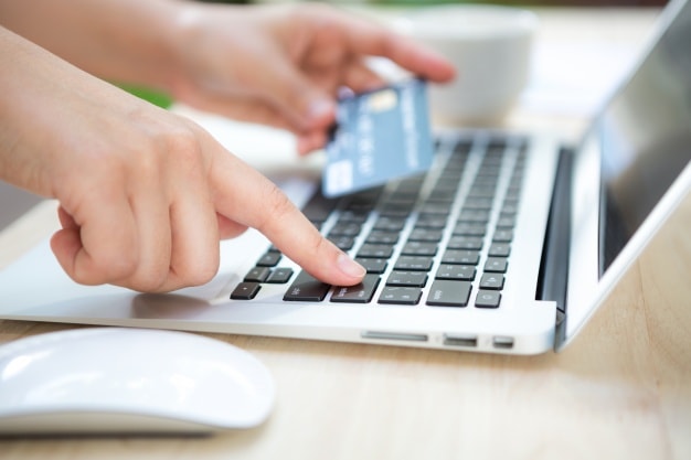 Hands typing on a laptop with a credit card in hand, illustrating online purchasing and conversion rate improvement