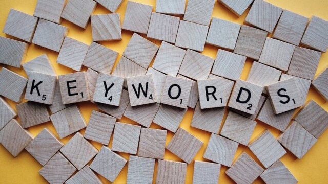 Scrabble tiles spelling KEYWORDS scattered on a yellow background