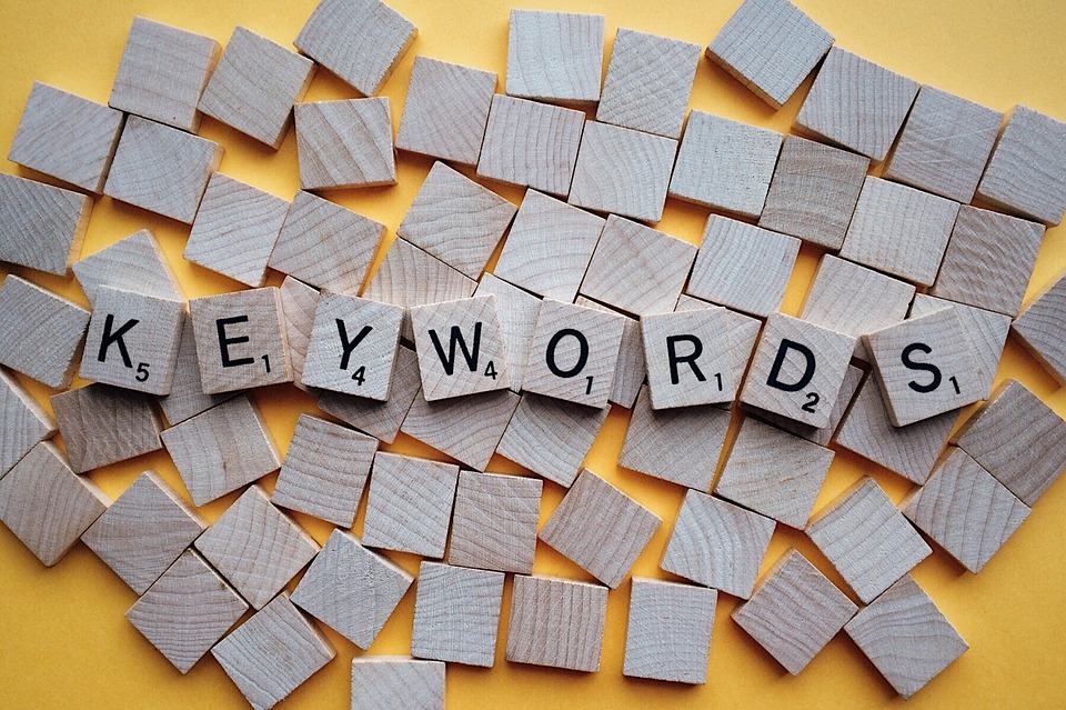 Scrabble tiles spelling KEYWORDS scattered on a yellow background