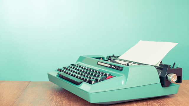 Vintage teal typewriter with blank paper on a wooden desk, representing content writing and optimisation