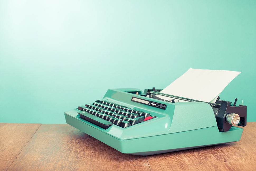 Vintage teal typewriter with blank paper on a wooden desk, representing content writing and optimisation