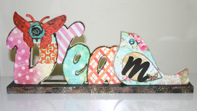Colourful decorative wooden letters spelling DREAM on a display stand, representing the DREAM outreach model