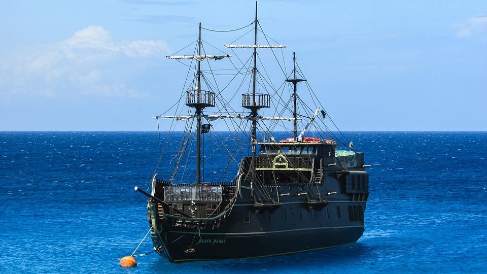 Black wooden pirate ship named Black Pearl anchored on calm blue ocean water
