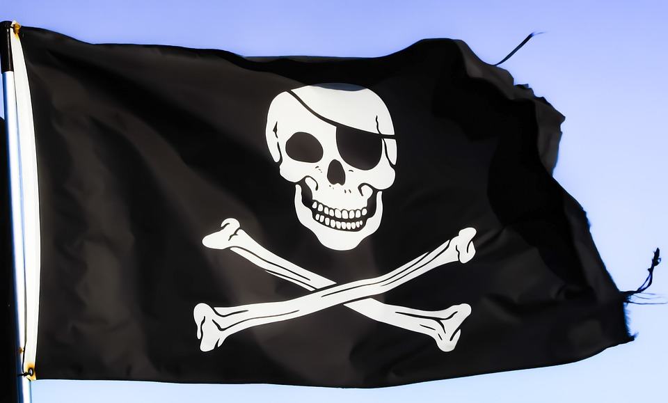 Jolly Roger pirate flag with skull and crossbones waving against a blue sky