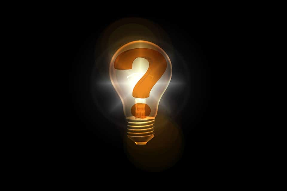 Glowing light bulb containing a question mark against a dark background, representing SEO questions