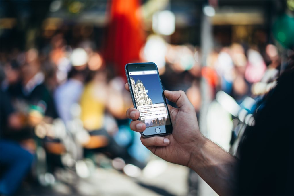 Person holding a smartphone showing the Samoa Police Service website in a busy outdoor setting