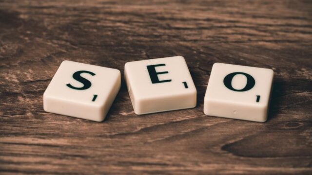 Three Scrabble tiles spelling SEO arranged on a rustic wooden surface