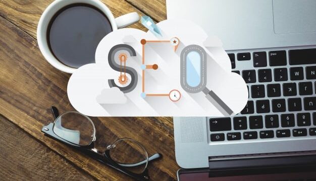 SEO letters inside a cloud graphic overlaid on a laptop and coffee cup on a wooden desk