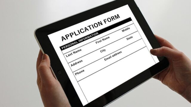 Hands holding a tablet displaying a job application form with personal information fields