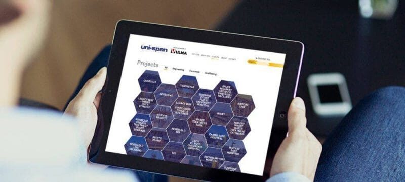 Person holding a tablet displaying the Uni-span projects page with a hexagonal grid layout