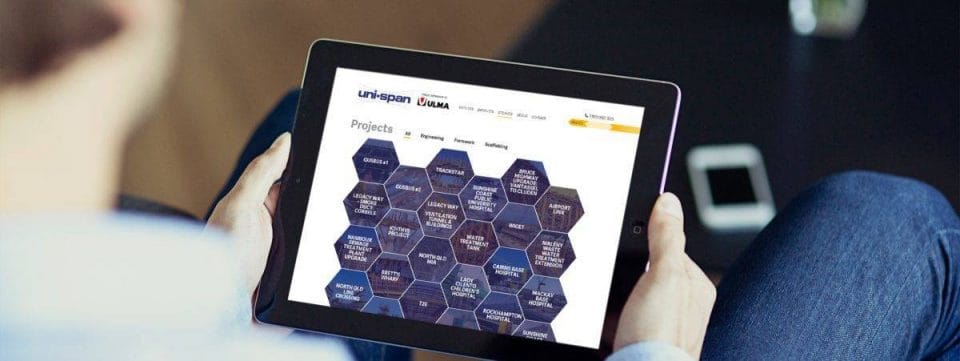 Person holding a tablet displaying the Uni-span projects page with a hexagonal grid layout