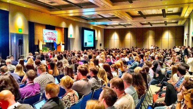 Packed conference hall at WordCamp with hundreds of attendees watching a presentation on stage
