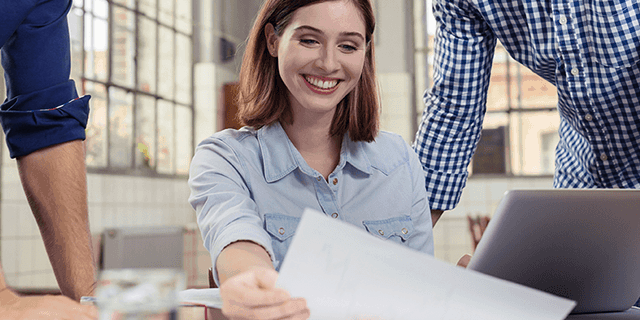 Smiling woman reviewing documents with colleagues, illustrating a WordCamp presentation about working without difficult clients
